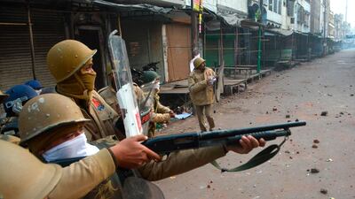 A police personnel aims his gun towards protesters during demonstrations against India's new citizenship law in Kanpur. AFP