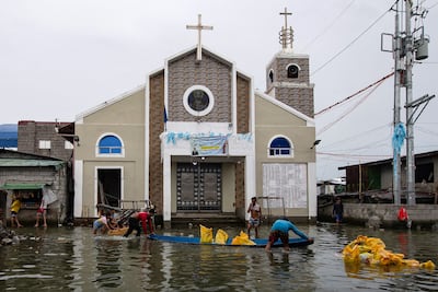 Workers line up sandbags outside a church in a flooded street on Pugad. AFP