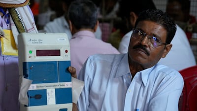 An election official displays an electronic voting machine after unsealing it to count votes in Lucknow. AP