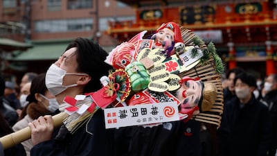 A man holds a kumade - a bamboo rake decorated with symbols for good fortune - on his way to offer prayers for prosperity on the first business day of the year at the Kanda Myojin Shrine in Tokyo, Japan. EPA