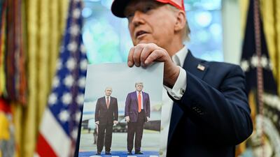 US President Donald Trump holds a photo of him with Russian President Vladimir Putin in Alaska. EPA