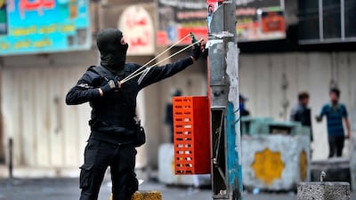 An anti-government protester uses a slingshot to fire a stone at security forces during clashes in Baghdad, Iraq. AP Photo