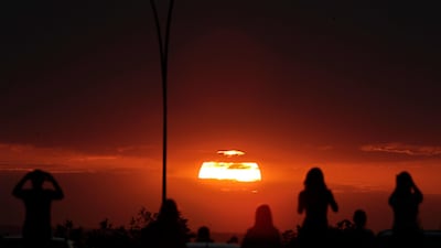 People watch the sunset before a partial lunar eclipse in the skies of Brasilia, Brazil. AP Photo/Eraldo Peres