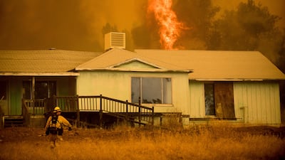 Flames rise behind a vacant house as a firefighter works to halt the Detwiler fire near Mariposa, California. Noah Berger / AP Photo