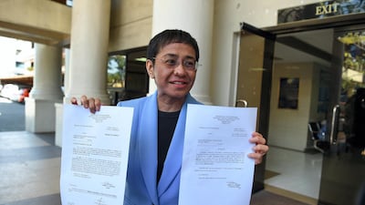 Maria Ressa, chief executive and executive editor of online portal Rappler, shows a warrant of arrest order after posting bail at a court in Manila on December 3. AFP