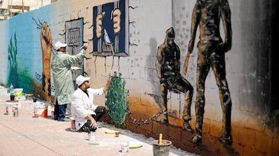 An artist paints a depiction of the microscopic view of the coronavirus chained to a prisoner as part of a mural in support of Palestinian prisoners held in Israeli jails in Gaza City. REUTERS