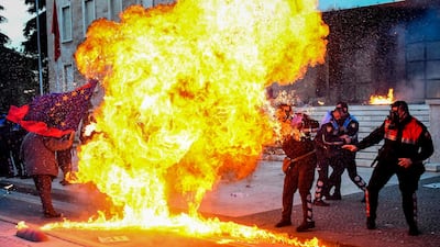 Albanian policemen attempt to avoid a petrol bomb thrown during protests in Tirana. AFP