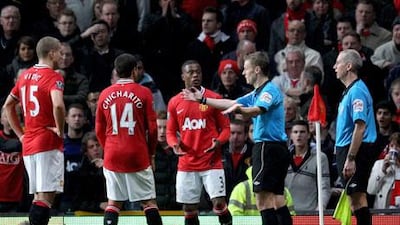 Michael Jones, the referee, gestures to the Manchester United players after consulting with his assistant John Flynn, right, who overruled the match official to award Newcaslte a dubious penalty at Old Trafford.