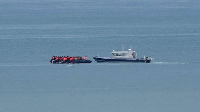 A boat carrying migrants is escorted by a police vessel in the English Channel off northern France last month. AP