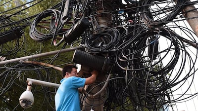 A worker makes repairs below electricity and communications cables on a pylon in Beijing on September 5, 2014. Shanghai stocks closed at a 17-month high on September 5 on hopes the Chinese government will introduce fresh measures to kickstart the world's number two economy. Greg Baker / AFP