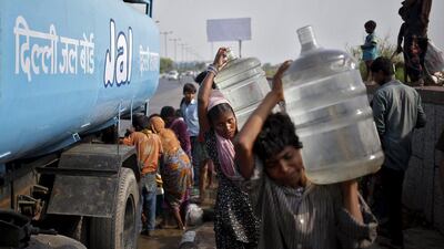Slum dwellers carry drinking water containers which they filled from a water tanker provided by the state-run Delhi Jal (water) Board on a hot summer day in New Delh. Anindito Mukherjee / Reuters