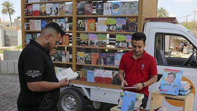 Ali Al Moussawi, right, the owner of a mobile book lorry, arranges his books on a street in Baghdad, Iraq. Karim Kadim/AP Photo