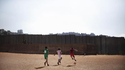 Palestinian boys play football in front of the controversial Israel separation barrier in the West Bank village of Anata. (Marco Longari / AFP)