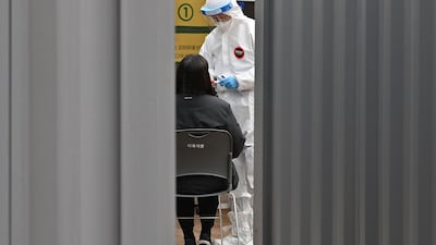 A medical staff member takes a swab from a visitor to test for the Covid-19 coronavirus at a temporary testing station outside the City Hall in Seoul. AFP