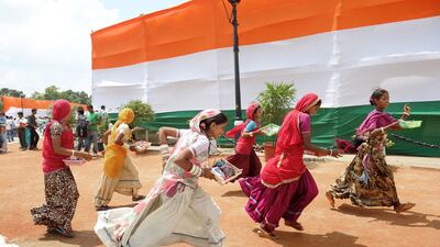 Women selling trinkets to visitors at the India Gate monument in New Delhi run as a policeman chases them away on August 15, 2012. Roberto Schmidt / AFP Photo