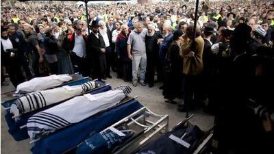 Mourners stand around the bodies of Ehud Fogel, 36, his wife Ruti, 35, and their children, 11-year-old Yoav, 4-year-old Elad, and 3-month-old Hadas, during their funeral in Jerusalem.