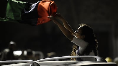 A Libyan woman holds up the rebel adopted pre-1969 national flag during celebrations, after rebel forces overran Libyan leader Moamer Kadhafi's fortified Bab al-Azizya headquarters in the capital Tripoli, following heavy fighting on August 23, 2011. AFP P???