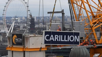 Workers take down a sign showing the name of liquidated British construction and outsourcing group Carillion from a construction crane on a building site in the City of London on January 23, 2017. AFP / Daniel SORABJI