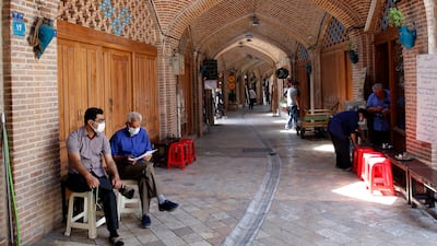 Iranians sit next to their closed shops at the old grand bazaar in Tehran.