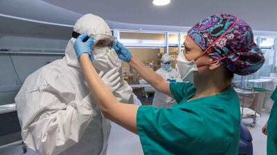 A nurse helps a colleague wear personal protective equipment (PPE) at the Intensive Care Unit (ICU) of Morales Meseguer Hospital in Murcia, Spain, 25 April 2020. Marcial Guillen/ EPA