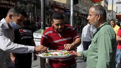 A man distributes sweets to passers-by in Amman on the occasion of the Prophet Mohammed's birthday on October 29, 2020. Health officials say public failure to follow safety guidelines is pushing up Covid-19 infections in Jordan. Reuters