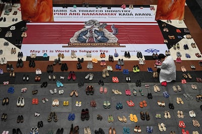 A doctor takes a photo of an art installation with shoes signifying the number of deaths caused by smoking, at the Lung Centre of the Philippines in Quezon City, on May 31, 2022. AFP