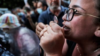 A protester holds up an image of three of the Beirut blast victims during a demonstration outside the residence of Lebanon's interior minister in the Qoraitem neighbourhood of western Beirut.