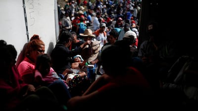 Carol Santos, a migrant from Honduras, fans her baby with a hat as they hitch a ride with fellow migrants in the back of a truck near Sayula de Aleman, Mexico. Reuters
