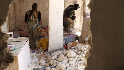 Female PKK fighters walk through destroyed houses in Sinja. Asmaa Waguih / Reuters
