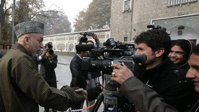 The Afghanistan president Hamid Karzai, left, greets journalists after the Eid al Adha prayers at the Presidential Palace mosque in Kabul, Afghanistan, on Friday, November 27, 2009.