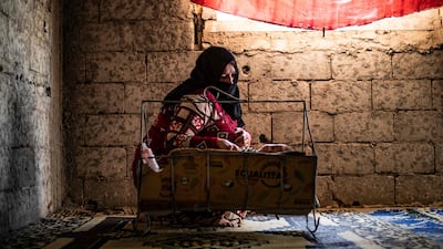 A Syrian mother, displaced with her family from Deir Ezzor, rocks a baby to sleep inside the damaged building where she is living in Syria's northern city of Raqqa.