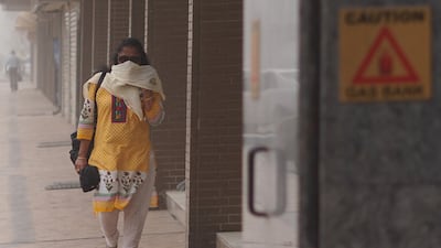A woman in Dubai covers her mouth during a dusty, hazy day in Dubai. Delores Johnson / The National
