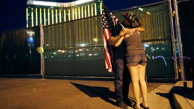 Kenneth Wright embraces Cara Knoedler on the anniversary of the Oct 1, 2017 mass shooting, in Las Vegas. Behind them is the site of the massacre. AP