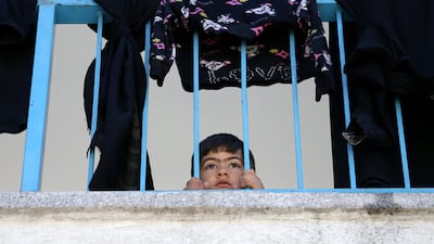 A Palestinian boy, who fled his family home due to Israeli bombardments, peers through railings of a UN-run school where he has taken refuge in Gaza city. Reuters