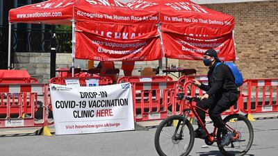 A cyclist rides past a Covid-19 vaccine drop-in vaccination clinic, in Hounslow, west London. AFP