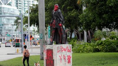 A woman walks past a vandalised statue of Juan Ponce de León at Bayfront Park in Miami. AP Photo