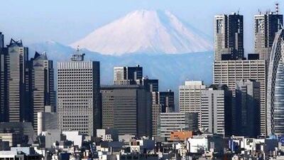 Mount Fuji, Japan's highest peak, looms over high-rise buildings of Tokyo's Shinjuku district. Kyodo News via AP Photo