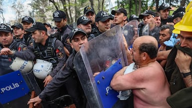 Protesters face riot police during a topless rally staged by scores of miners outside Turkey's Energy Ministry headquarters to demand unpaid wages, in Ankara. AFP