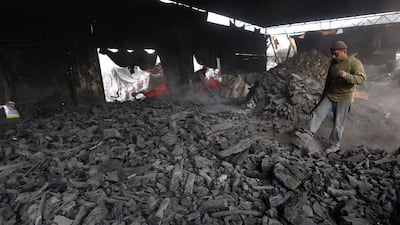 A worker spreads charcoal for cooling in the West Bank village of Yabed. The charcoal is made of citrus wood the workers say comes from Israel, and is later sold to Israelis and Palestinians for approximately 10 shekels (US$2.70) a kilo. Alaa Badarneh / EPA