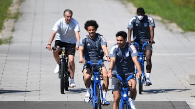 Germany's Leroy Sane and Ilkay Gundogan ride bicycles with teammates before training. Reuters