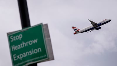A British Airways flight takes off from Heathrow Airport behind a sign against its development. EPA