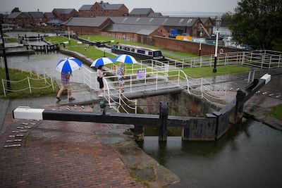 Visitors to the National Waterways Museum in Cheshire, England, are caught in a rain storm. Getty