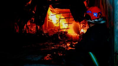 A firefighter attempts to put out the flames after the multi-storey commercial building caught fire before collapsing. AP