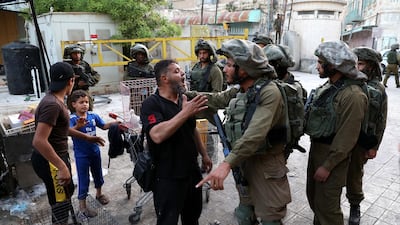 Israeli soldiers on patrol stop Palestinians in the Old City of the West Bank town of Hebron, May 17. EPA