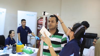 Farha Mansan checks labourer Bilal Uddin’s height and weight at a Pad health clinic held at IFFCO labour camp in Al Quoz. Sarah Dea / The National