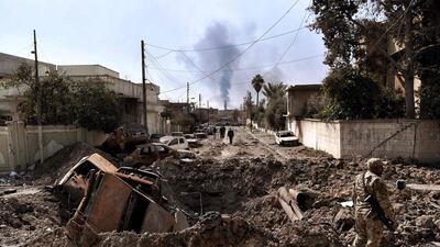 An Iraqi forces member stands next to a crater made by an air strike in west Mosul as Iraqi troops continue battling ISIL fighters to further advance inside the city on March 7, 2017. Aris Messinis/AFP