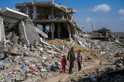 A Palestinian man and two girls stand a mid of the rubble of homes, destroyed by the Israeli army's air and ground offensive against Hamas in in Bureij refugee camp, central Gaza Strip, Monday, Feb. 17, 2025. (AP Photo / Abdel Kareem Hana)