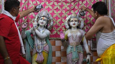 Priests pour milk and water on the idols of Hindu deities Krishna and Radha on the eve of Janmashtami in Amritsar. AFP