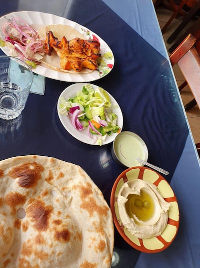 Dh15 at Al Ibrahimi restaurant gets you a plate of veggies, a cucumber-mint raita, bowl of hummus, one-fourth of a chicken and bread. Photo: Rob McKenzie for The National