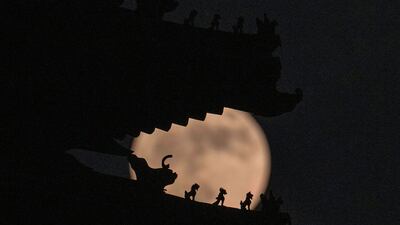 Roof decorations on the corner tower at the Forbidden City depicting sacred beasts are silhouetted against the Supermoon, in Beijing. AP